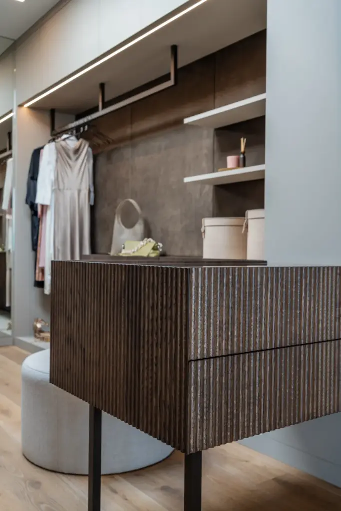 Maßgefertigter Ankleidebereich mit gerillter Holzfront und eleganten Ablagen von Deutschmann Moebel Handwerk