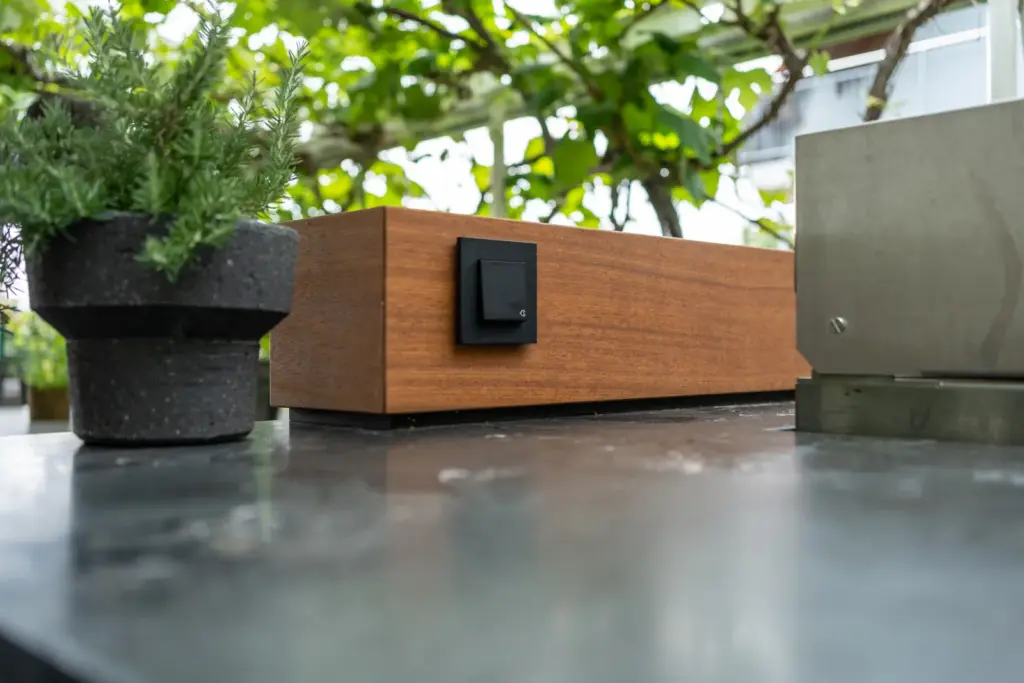 Arbeitsfläche aus dunklem Stein mit Holzaufsatz und stilvollem Schalterelement