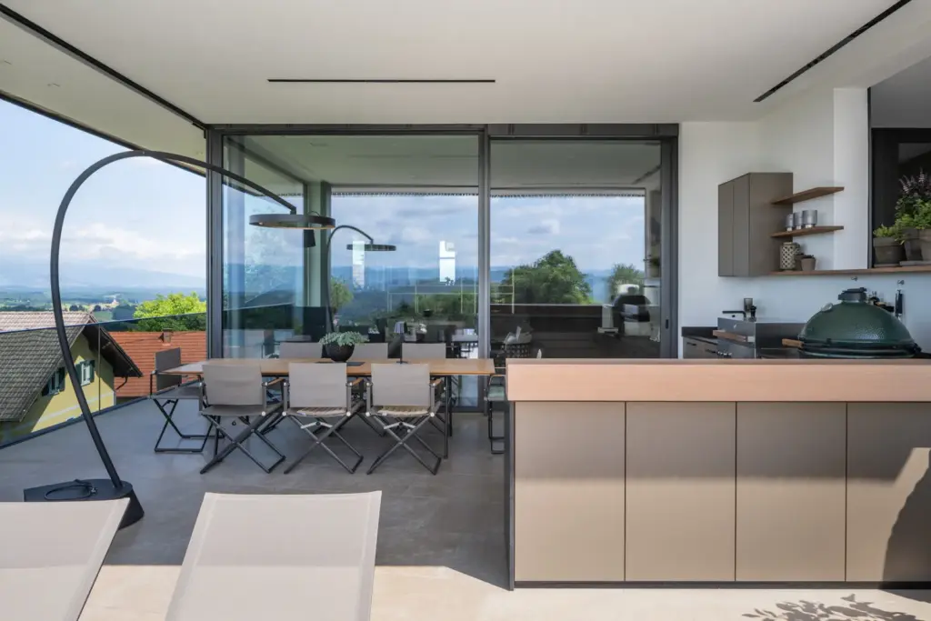 Überdachte Terrasse mit Outdoorküche und Esstisch mit Blick auf die Landschaft umgesetzt von Deutschmann