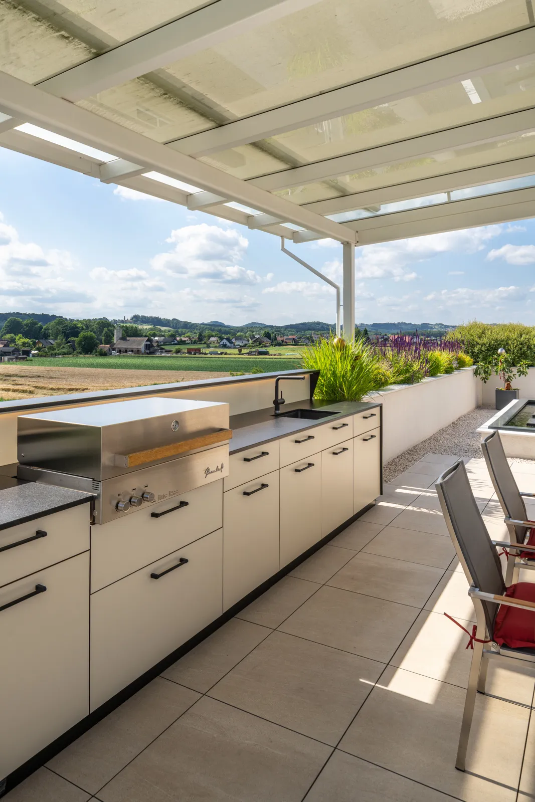 Wetterfeste Deutschmann Outdoorküche in hellen Farben mit Flammkraft Grill auf einer Terrasse