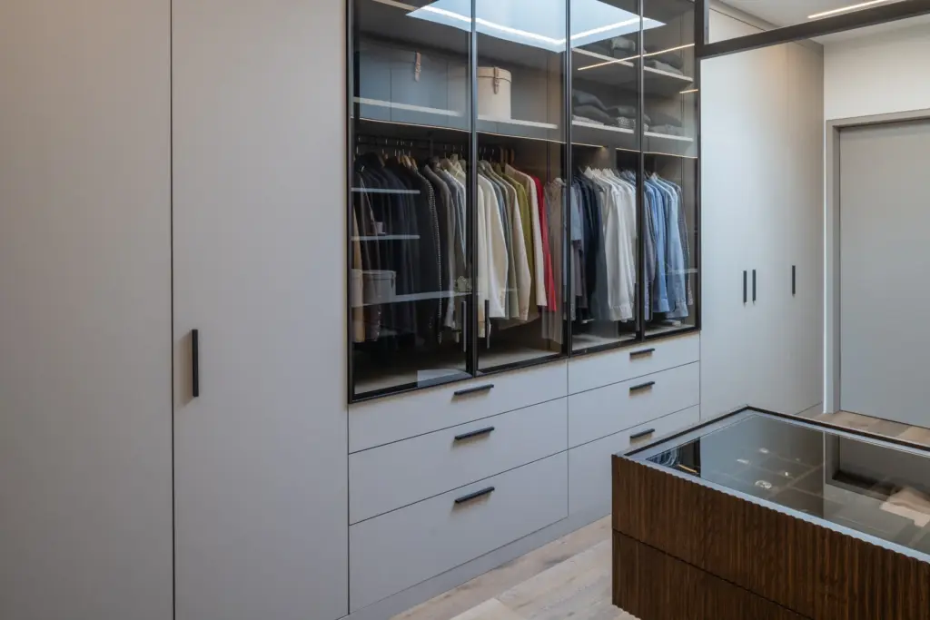 Eleganter Ankleideraum mit Glasfronten Schubladen und zentralem Möbelstück von Deutschmann