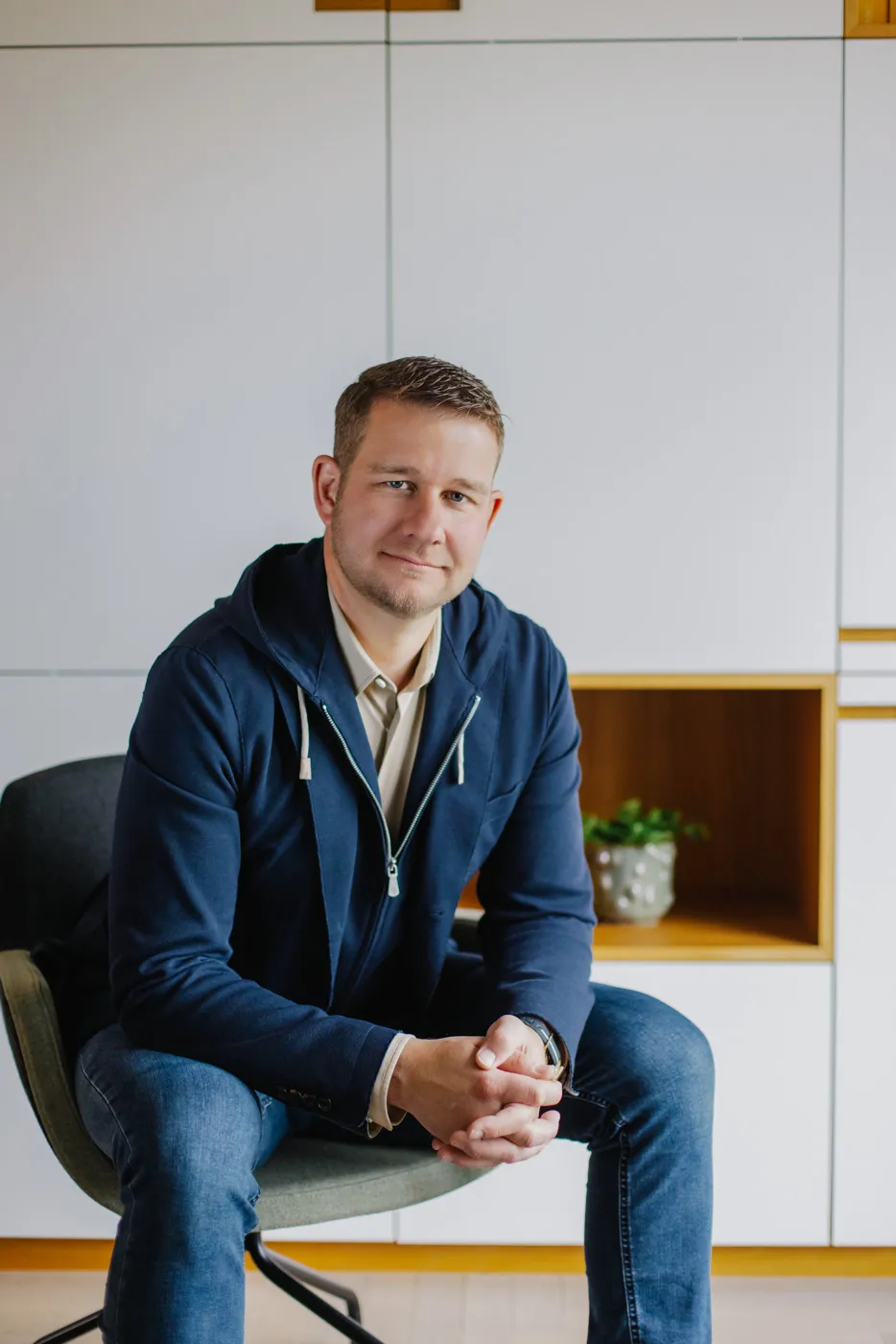 Sepp Deutschmann sitzt entspannt vor einem modernen Maßschrank aus der hauseigenen Tischlerei