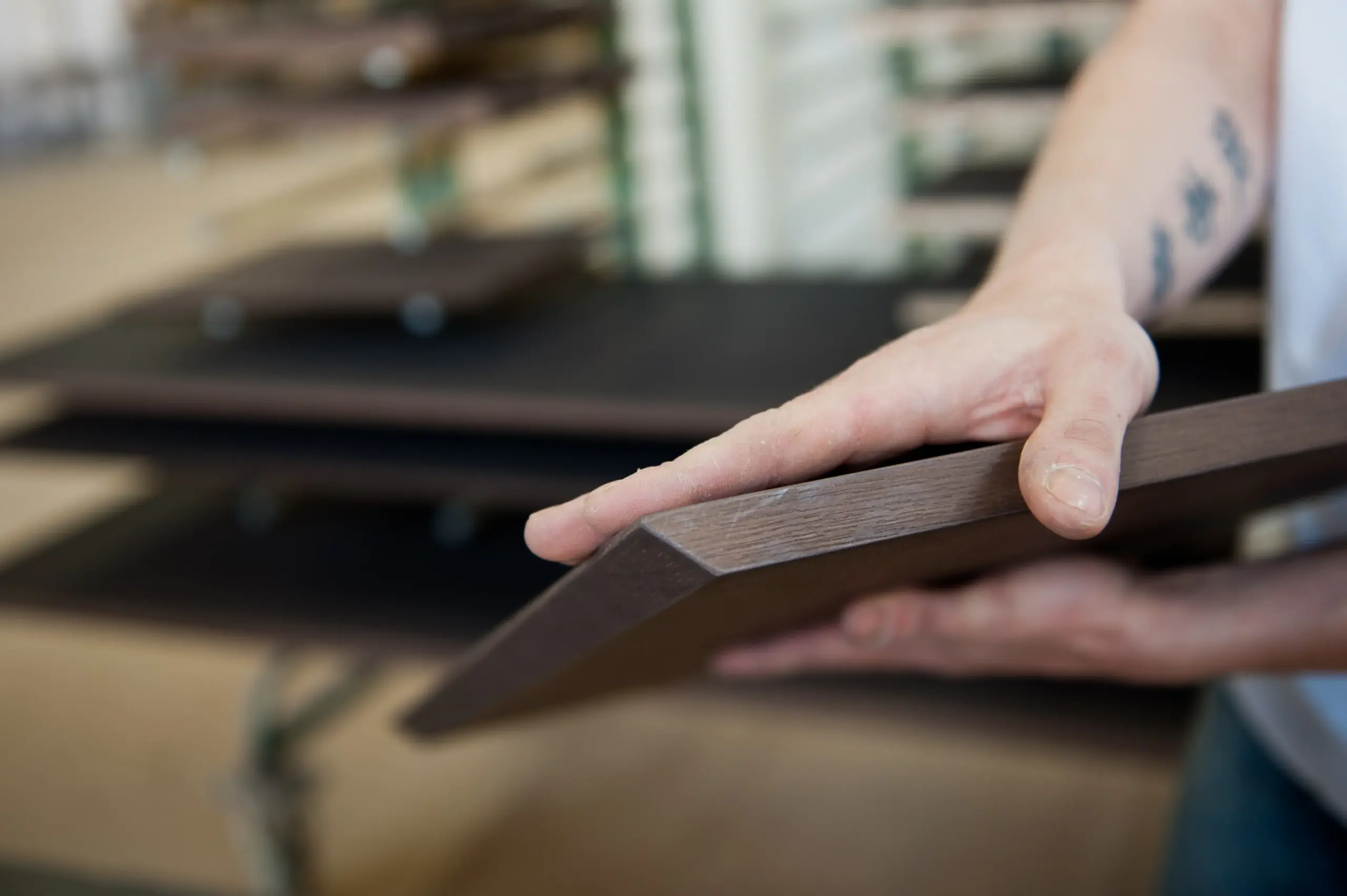 Tischler hält präzise zugeschnittene Holzplatte in der Werkstatt von Deutschmann
