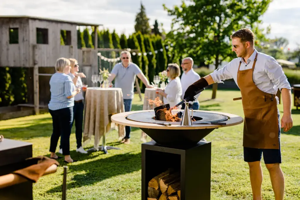 Deutschmann Grillkurs am OFYR Grill in einem Garten mit Menschen und warmer Atmosphäre