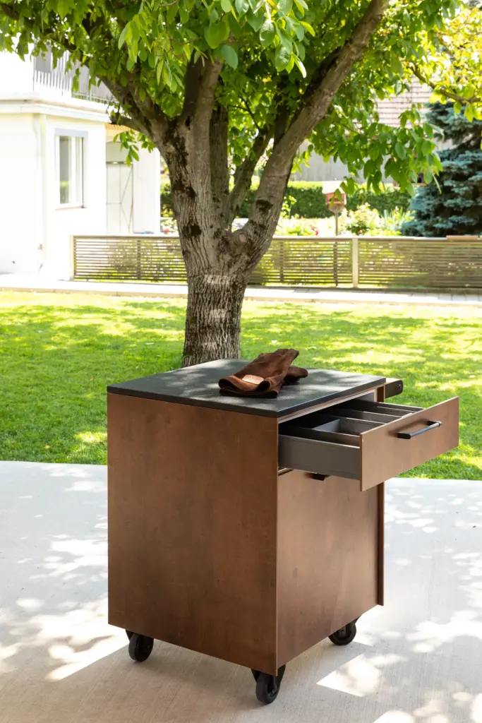 Beistellwagen von Deutschmann, offene Schublade mit Grillutensilien darin und einem OFYR Grillhandschuh auf der Arbeitsfläche des Beistellwagens