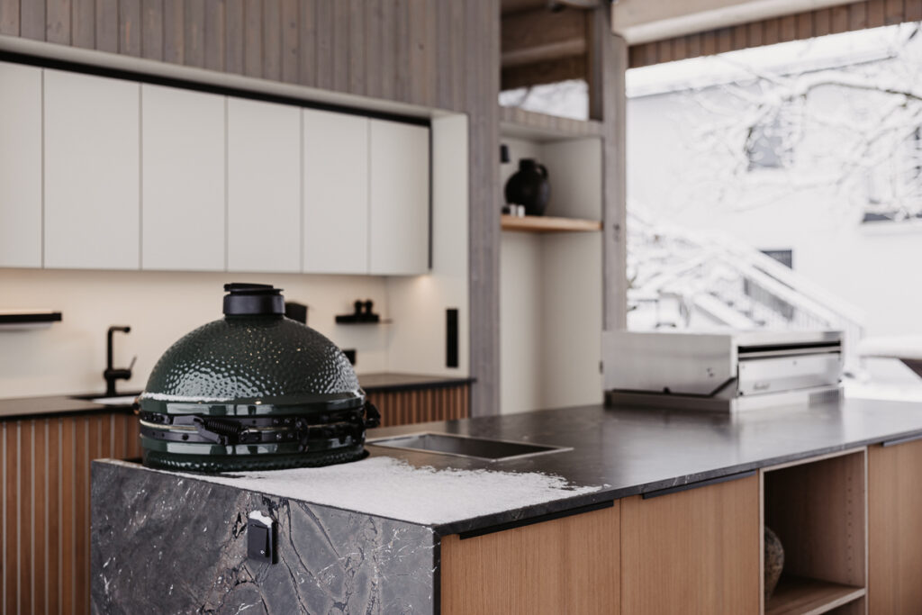 Deutschmann Outdoorküche mit leichten Schnee bedeckt und Big Green Egg Grill und Flammkraft Gasgrill integriert
