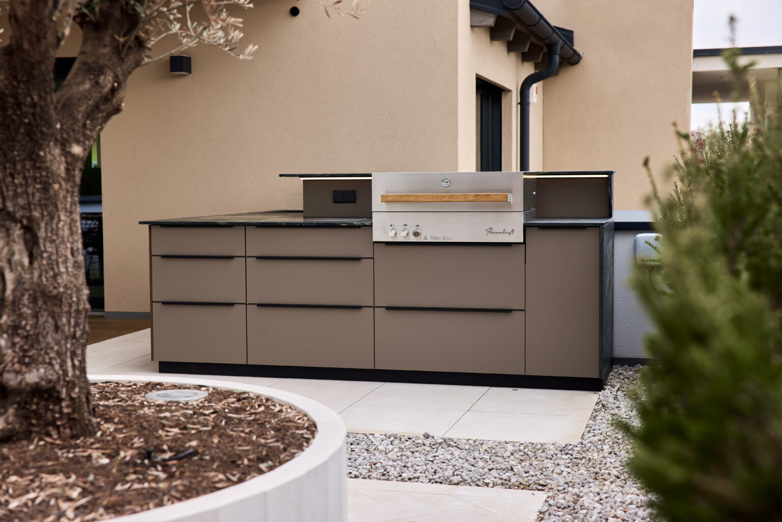 Beige Outdoorküche um das Eck einer Terrasse gebaut mit Flammkraft Gasgrill